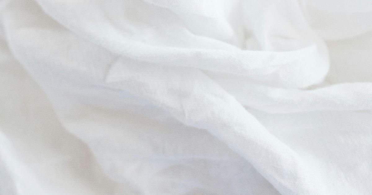 Close-up of soft, rumpled white linen bed sheets